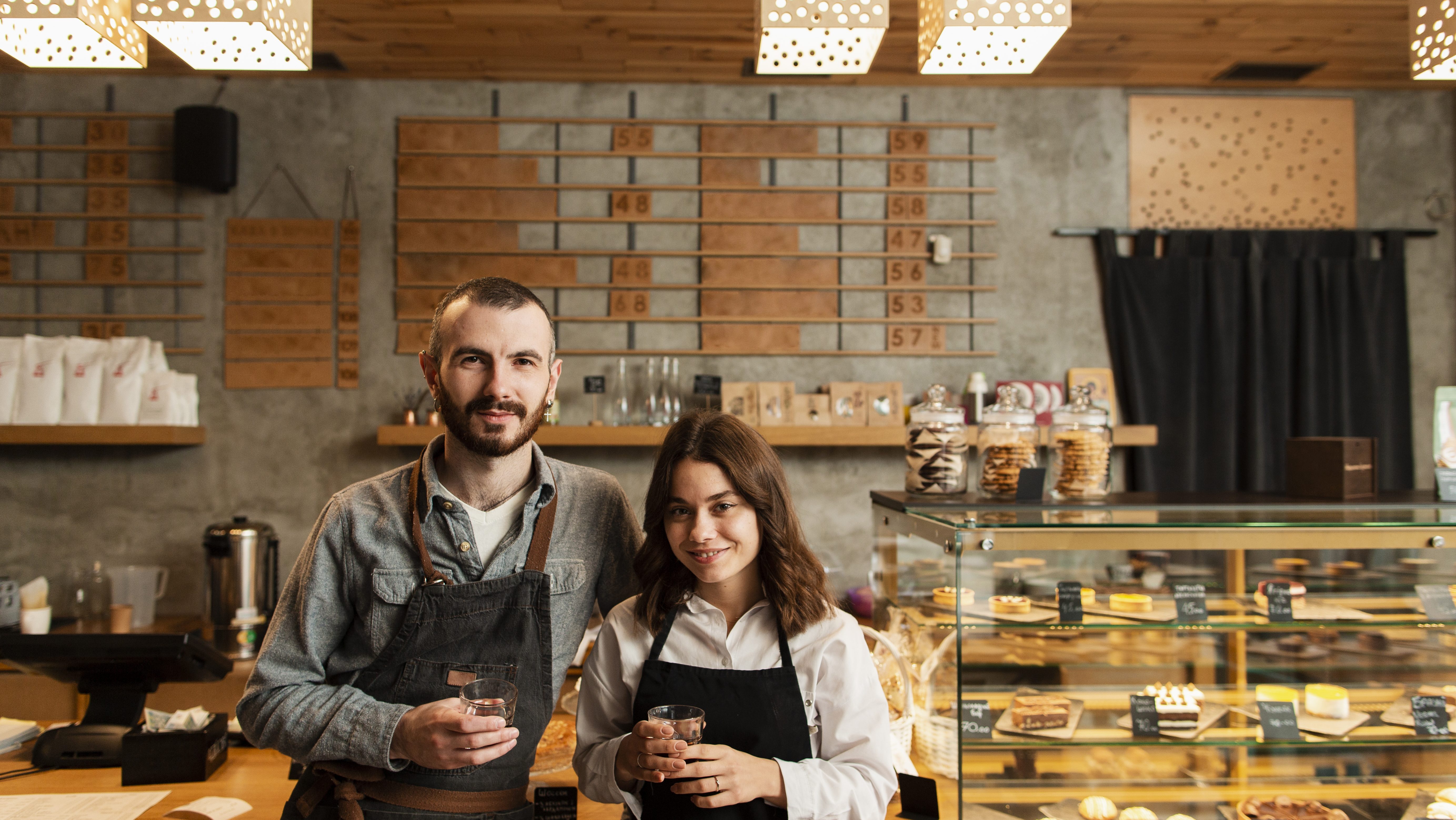 Mladi par osnivača kafe bara pozira sa kafom u rukama