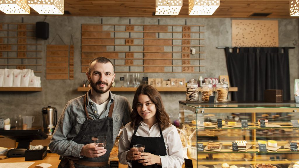 Mladi par osnivača kafe bara pozira sa kafom u rukama