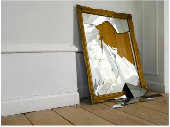 Broken mirror in the frame on the floor, the simbol of broken illusions