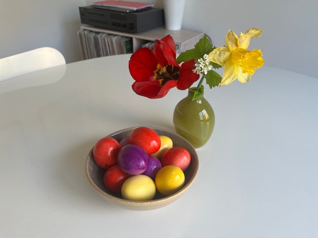 Uskrsnja jaja i vaza sa cvećem na stolu
