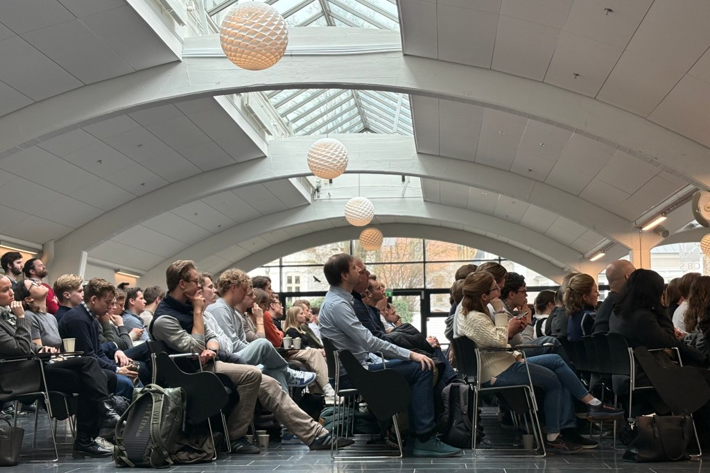 Publika sluša predavanje u hali pod dnevnim svetlom